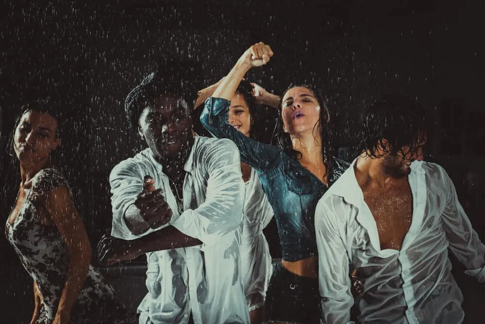 Abends tanzt eine Gruppe von Freunden im Regen