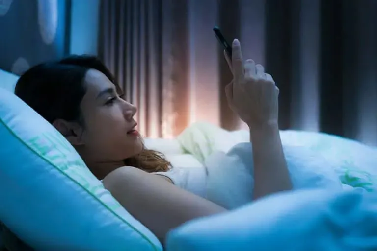 Frau schreibt SMS im Bett