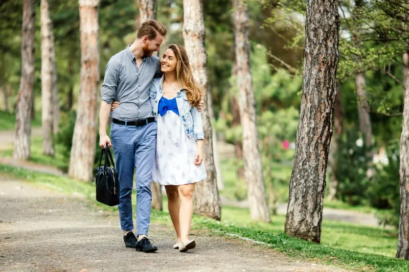 Ein Mann mit Bart und seine Frau in einem Kleid gehen durch den Park