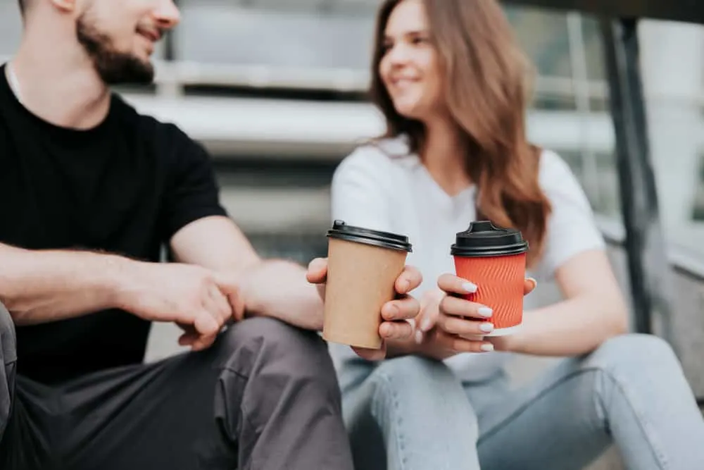 Ein Mann und eine attraktive Frau sitzen draußen und unterhalten sich beim Kaffee