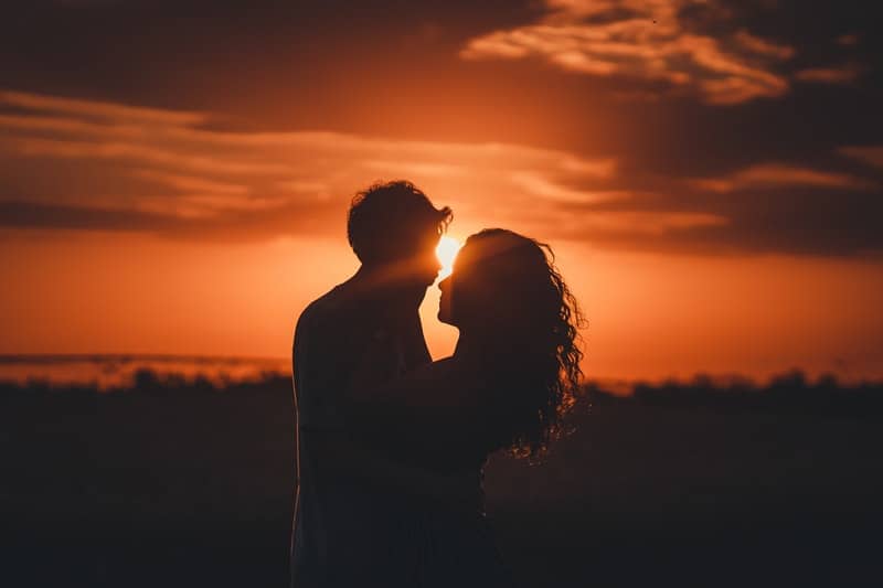 Eine Frau und ihr Mann küssen sich bei Sonnenuntergang