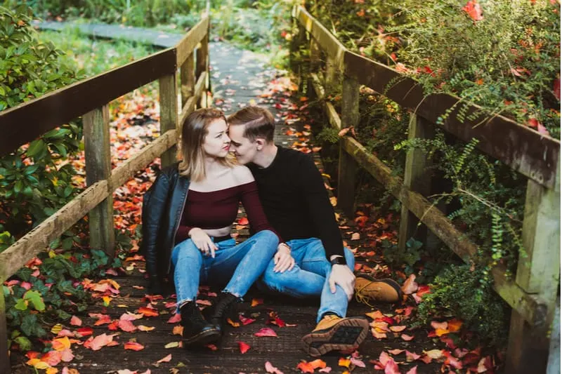 Im Herbst sitzt ein Liebespaar im Wald