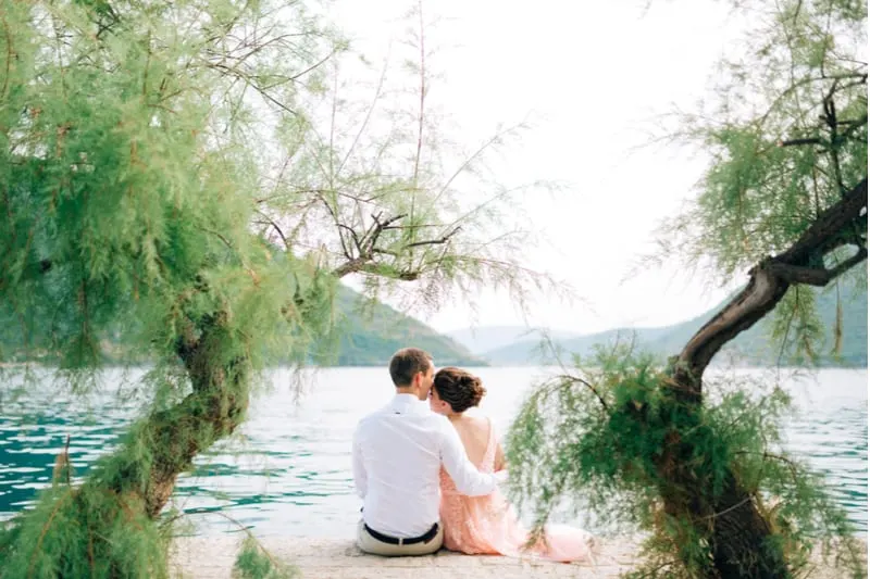 In der Nähe des Sees sitzt in einer Umarmung ein liebevolles Paar