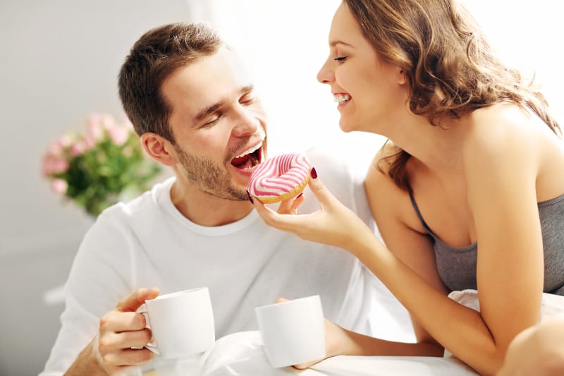 Morgenkaffee mit den Süßigkeiten eines liebenden Paares im Bett