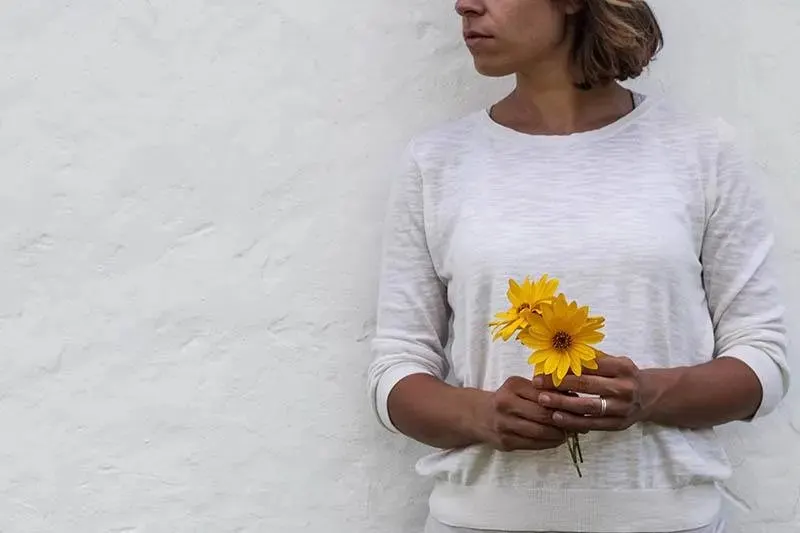Frau haelt gelbe Blumen
