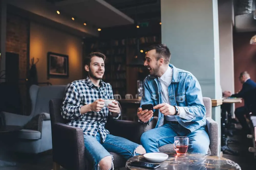 Zwei Männer sitzen in einem Café und reden und lachen