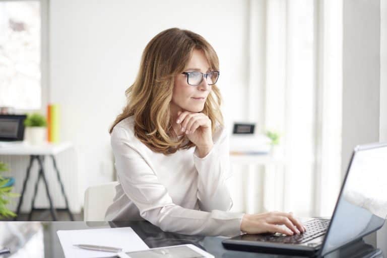 eine Frau mittleren Alters, die an einem Laptop arbeitet