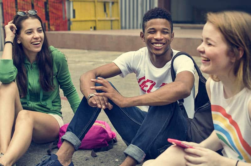 eine lächelnde Gruppe von Teenagern, die auf dem Asphalt sitzen