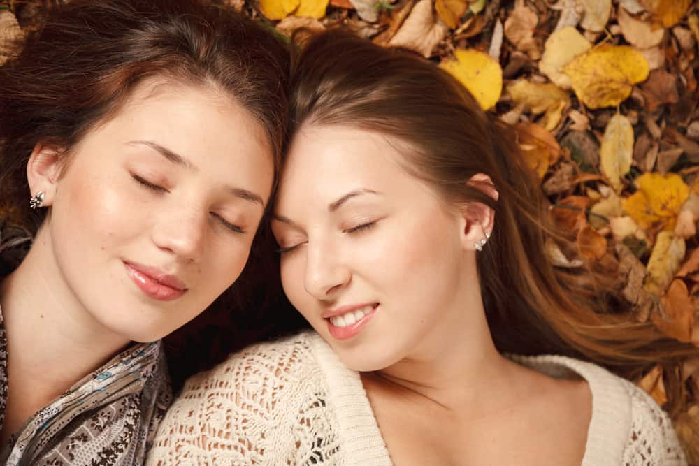 zwei Mädchen liegen auf trockenen Blättern und genießen