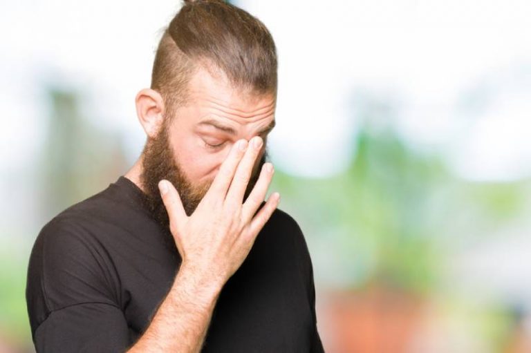 blonder Mann reibt sich die Nase