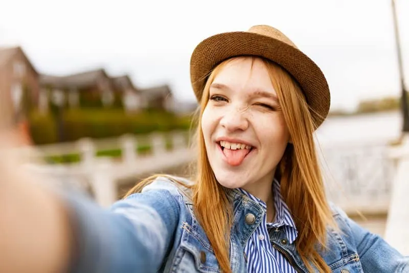 Das Mädchen mit dem Hut macht ein lustiges Selfie