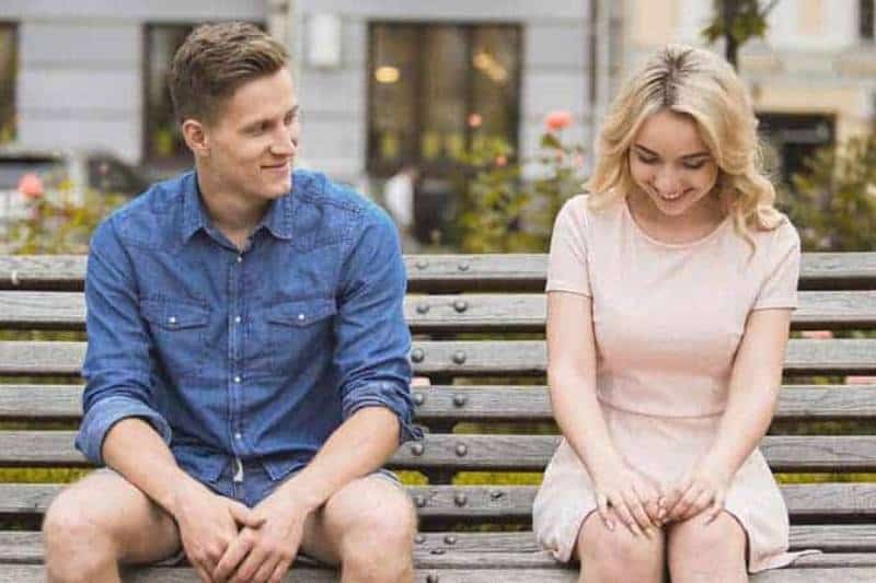Ein Mann und ein Mädchen sitzen auf einer Holzbank und flirten