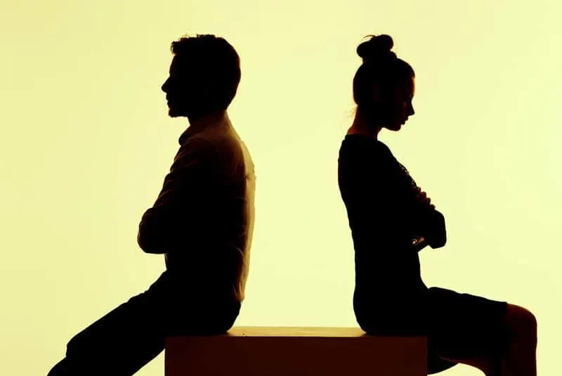 Ein Mann und eine Frau sitzen sich auf einem Würfel gegenüber