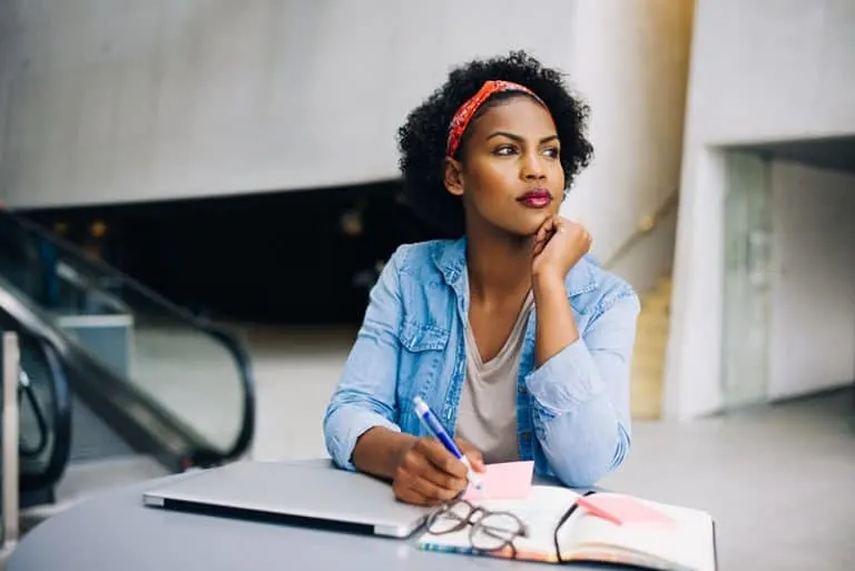 Eine besorgte junge schwarze Frau schreibt ein Tagebuch