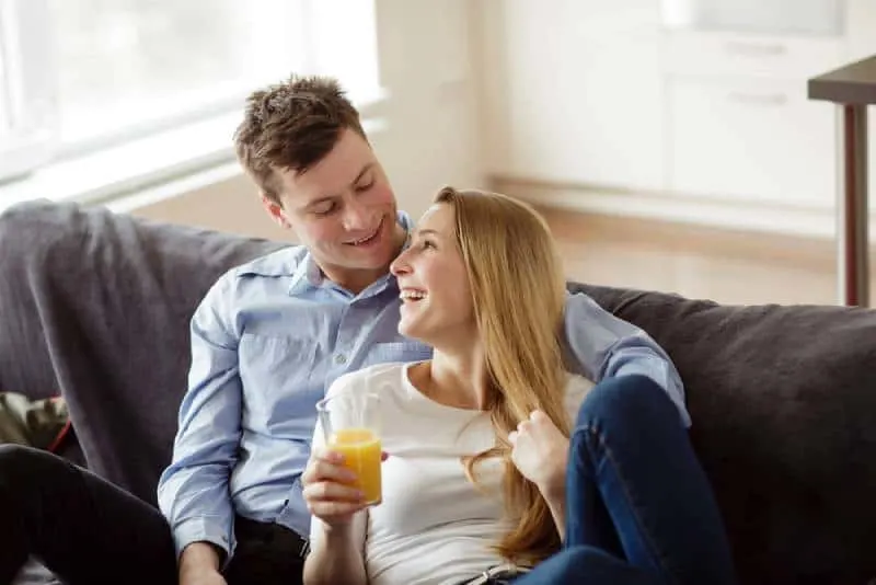 Junger Mann und Frau, die den Orangensaft entspannen und trinken