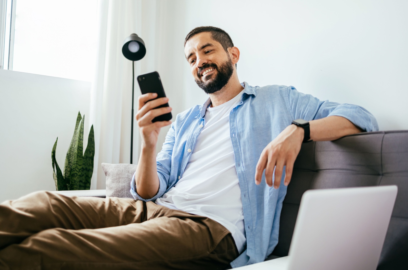 Mann laechelt und haelt ein Telefon