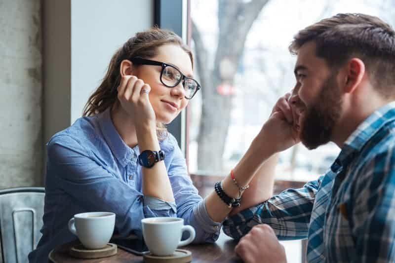 Ein verliebtes Mädchen in Gläsern trinkt Kaffee mit ihrem Freund