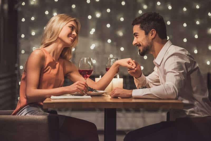 Schönes junges Paar schaut sich an und lächelt während ihres Dates in einem Restaurant,