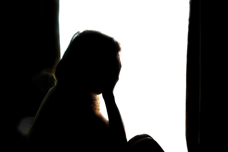 Silhouette einer traurigen Frau in einem dunklen Raum