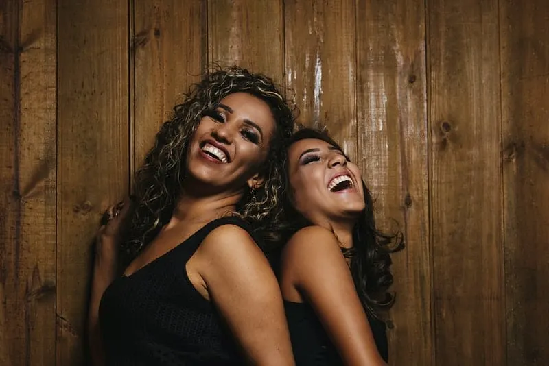 Zwei lächelnde schwarze Frauen stehen Rücken an Rücken
