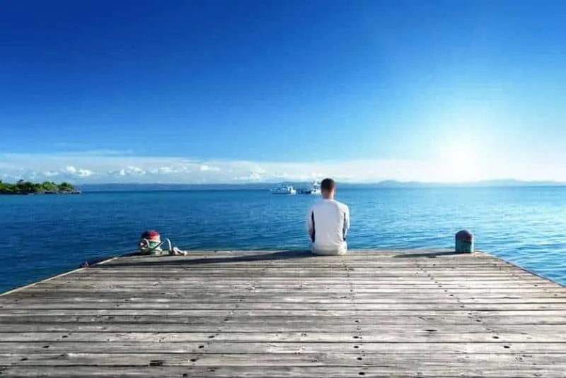 ein Mann, der alleine auf einem Seepier sitzt