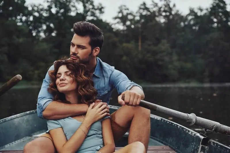 eine Frau, die in den Armen eines Mannes in einem Boot sitzt