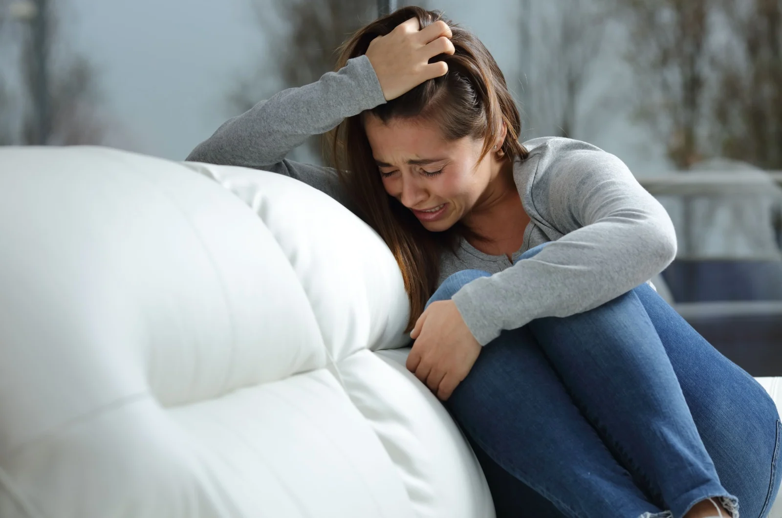 junge Frau weint auf der Couch