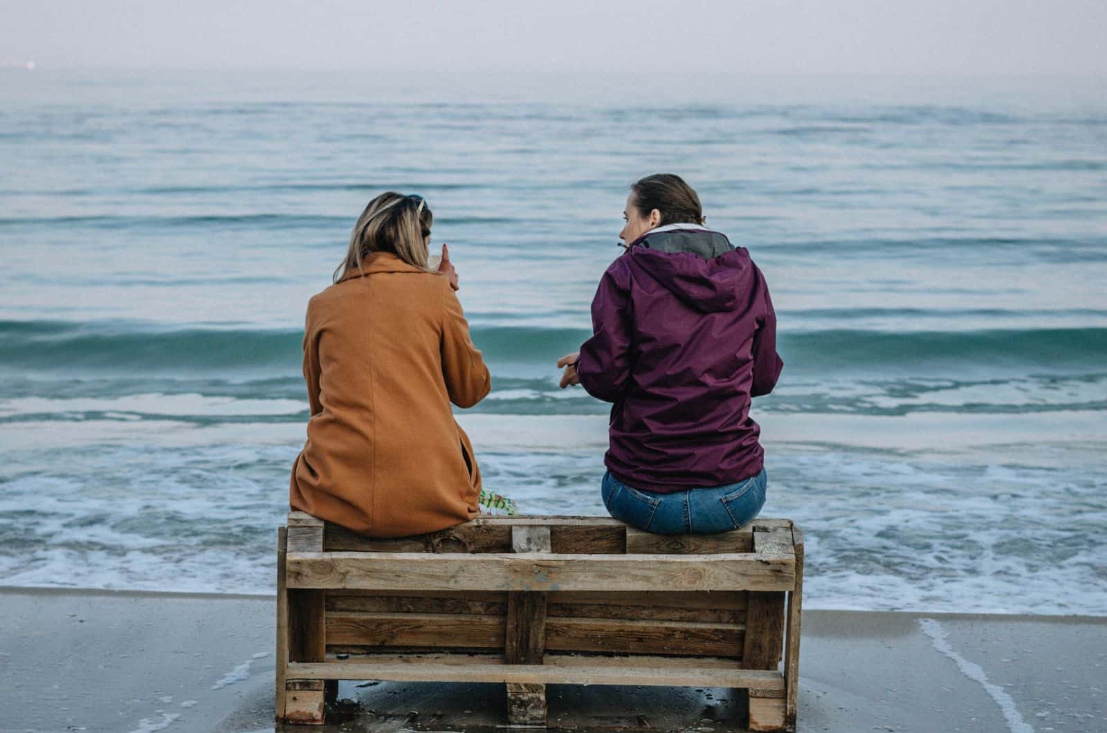 Zwei Frauen sitzen am Strand und unterhalten sich
