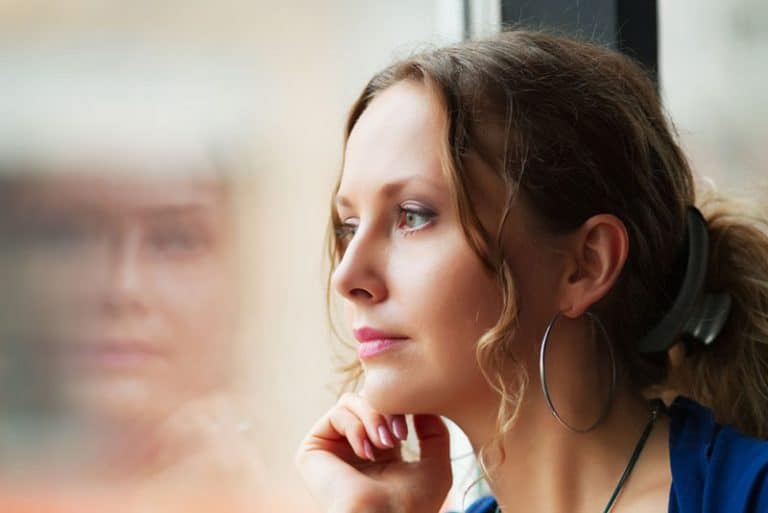 ein Mädchen, das am Fenster sitzt und den Regen fallen sieht