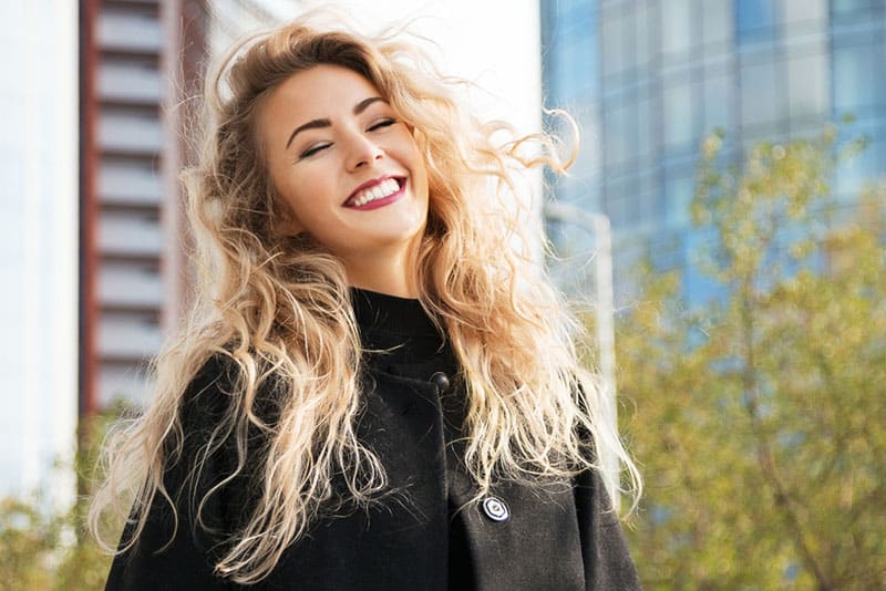 junge blonde Frau, die draußen lächelt