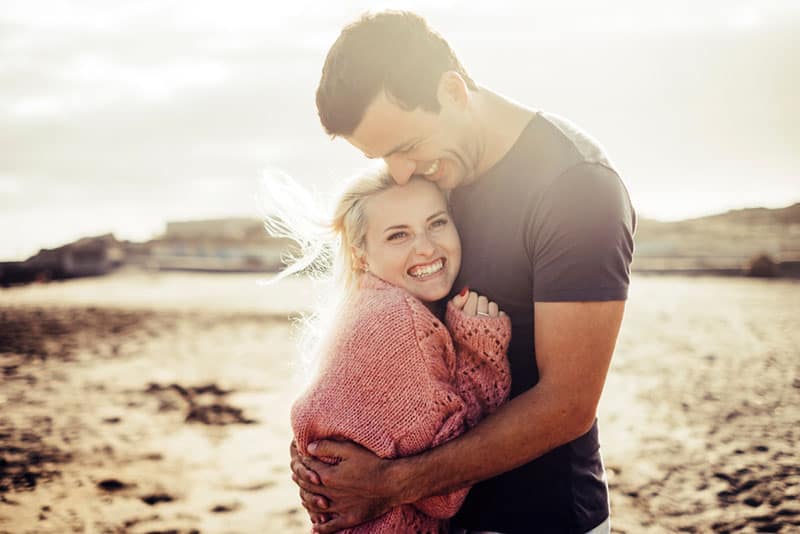 süßes Paar umarmt sich am Strand bei kaltem Wetter