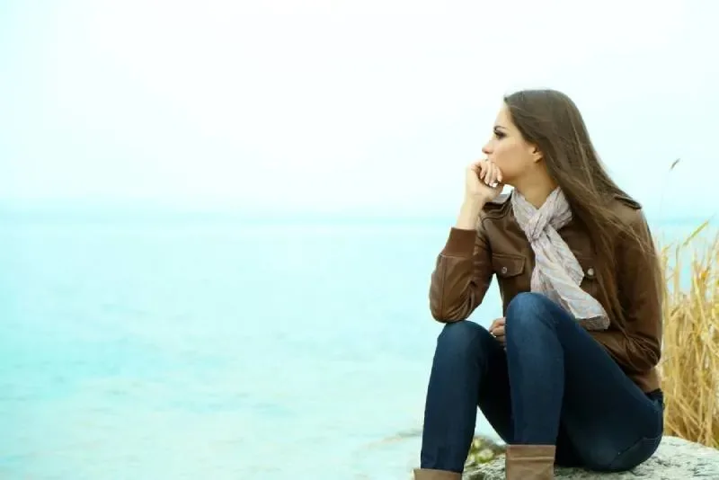 Frau sitzt am Meer