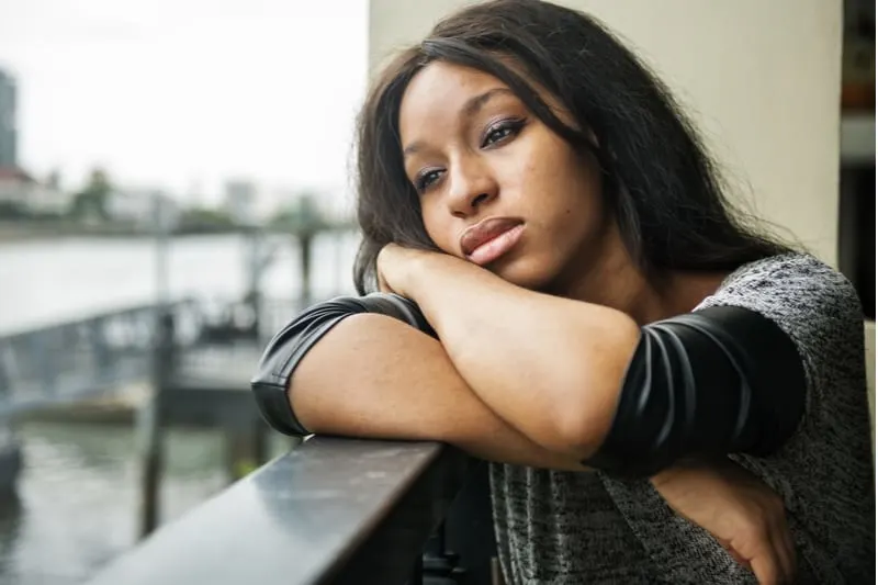 Eine depressive schwarze Frau sitzt auf dem Balkon
