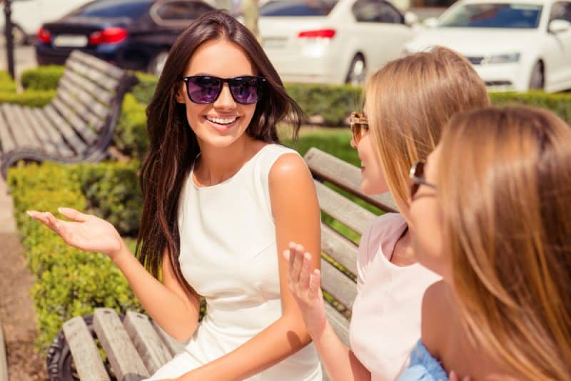 Fröhliche Frau spricht mit ihren Freunden auf einer Parkbank