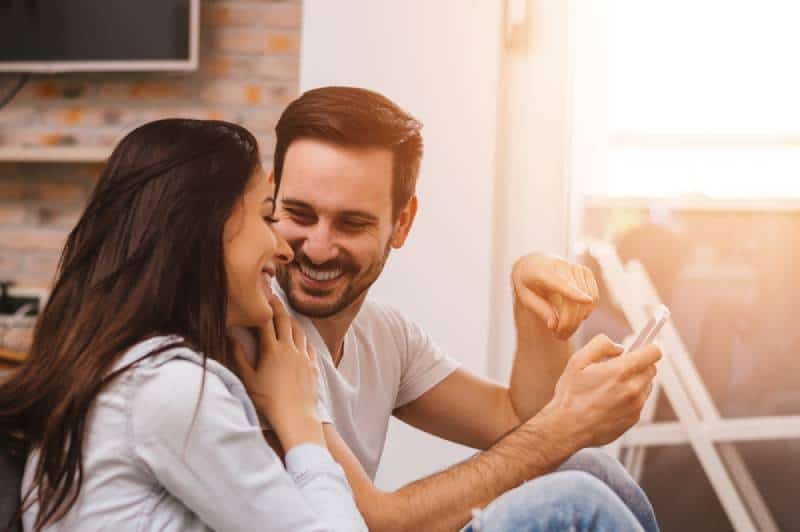 Mann hält Telefon, während lächelnde Frau es betrachtet
