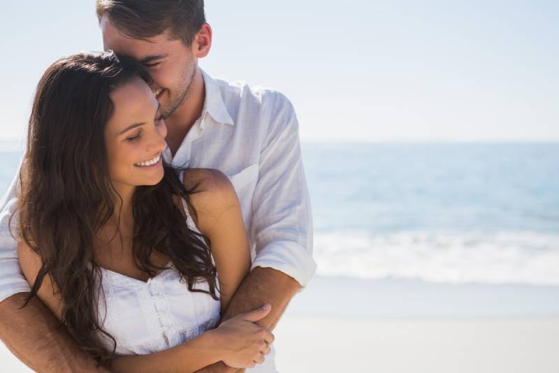Mann umarmt seine Freundin am Strand