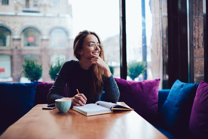 Mädchen mit Brille, die im Café schreibt