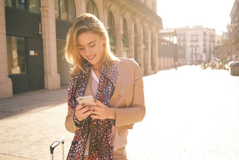 schönes blondes Mädchen, das am Telefon tippt