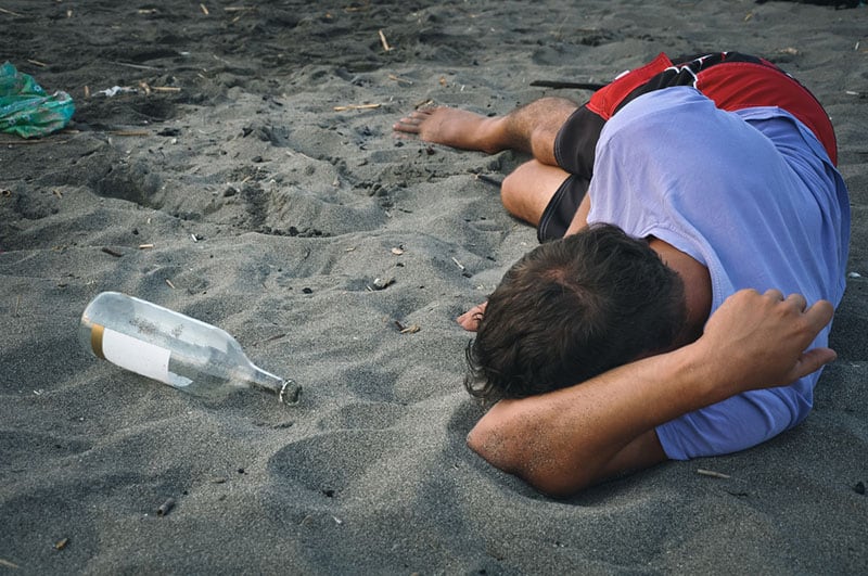 betrunkener Mann, der am Strand schläft