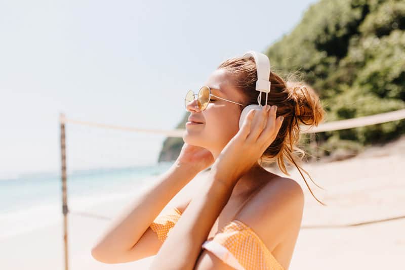 glückliche Frau, die Musik am Strand hört