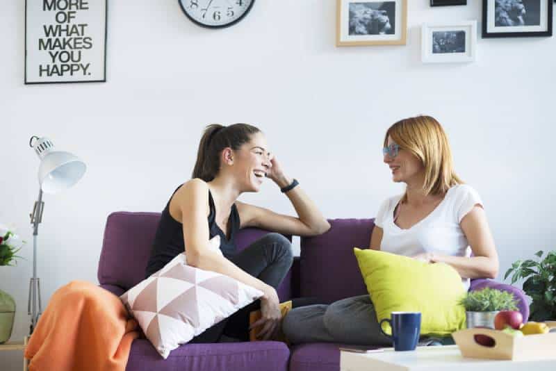 glückliche Freundinnen, die sich im Wohnzimmer unterhalten
