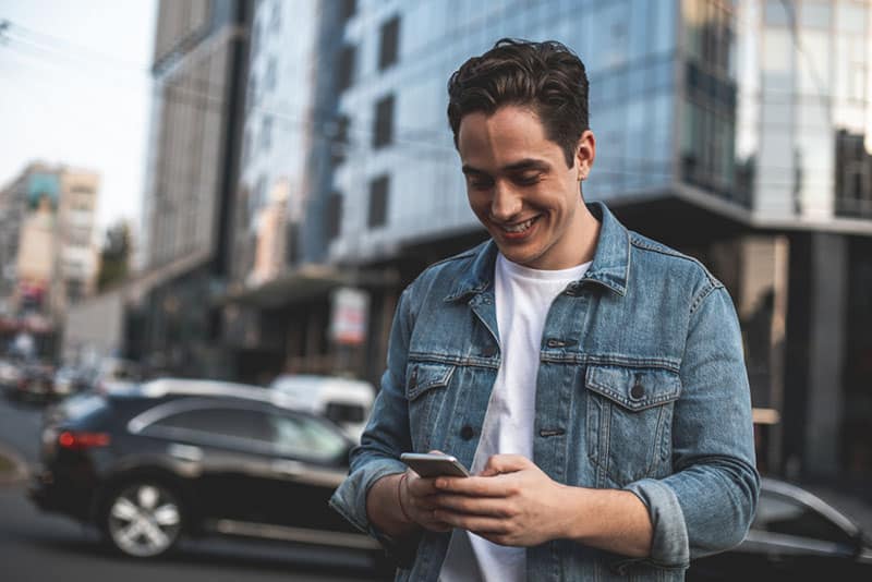 glücklicher Mann, der am Telefon eine SMS sendet