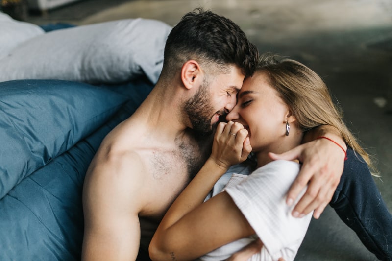 hübscher Mann und Frau küssen sich im Bett