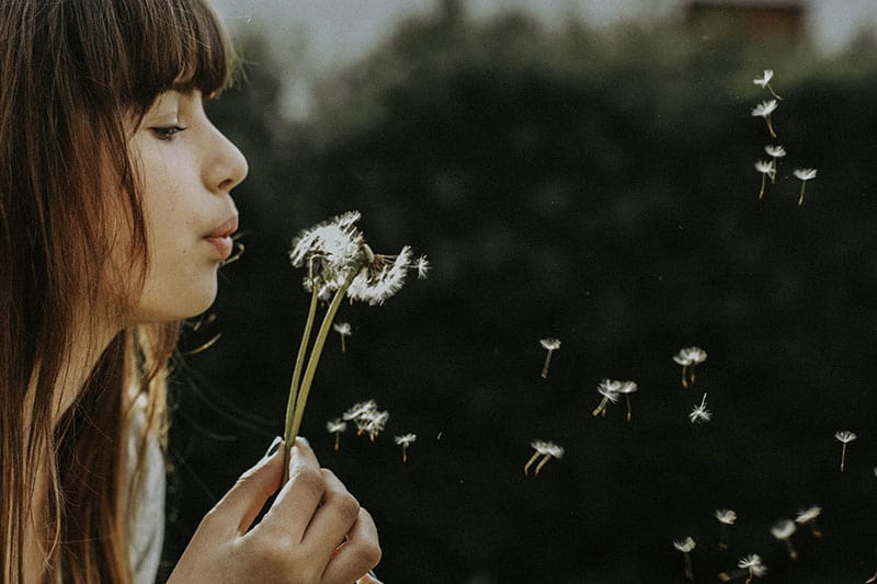 junge Frau, die die Blume bläst