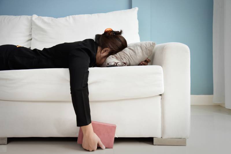 müdes Mädchen, das auf Sofa mit Kopf auf Kissen liegt
