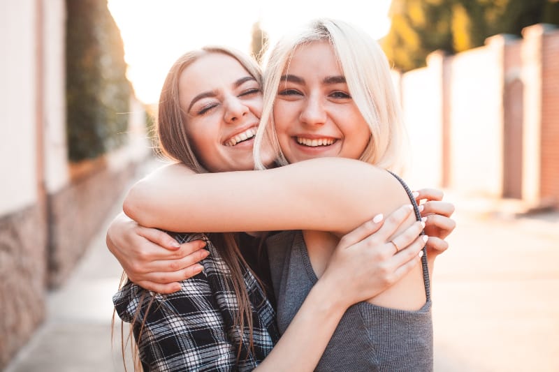 zwei attraktive junge Mädchen umarmen sich und lachen