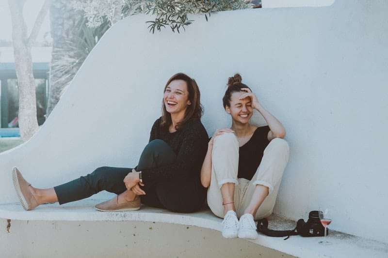 zwei Frauen lachen auf der Bank