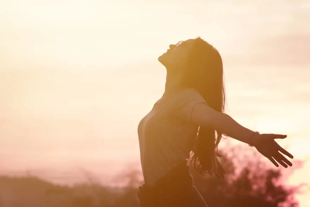 Frau fühlt sich draußen bei Sonnenuntergang fantastisch