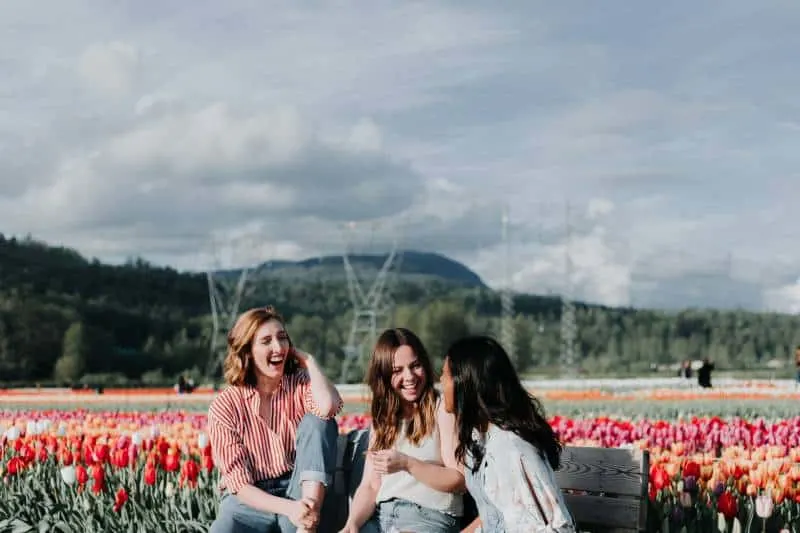 3 Frauen sitzen auf einer Bank in der Nähe der Blumen