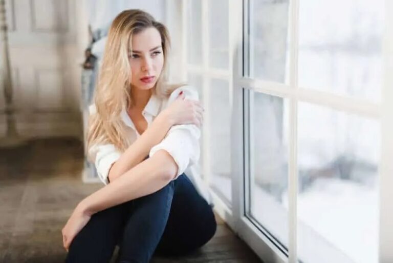 traurige Frau sitzt am Fenster